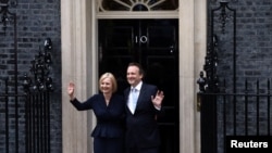 Лиз Тръс позира за камерите със съпруга си Хю О'Лиъри пред врата на резиденцията на британския премиер.
