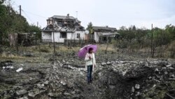O femeie stă în ploaie în mijlocul a ceea ce a fost cândva casa sa din Kramatorsk/Donețk.