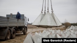 Робітник встановлює протитанкові укріплення «зуби дракона» біля кордону з Росією в Чернігівській області, 28 березня 2024 року