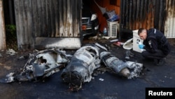 Офіцер поліції оглядає залишки російської крилатої ракети після чергової атаки, 18 травня 2023 року