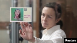 Журналистката Алсу Курмашева на изслушване в съда в Казан на 1 април 2024 г. До стъклото тя държи картичка с надпис „Очакват я у дома“.