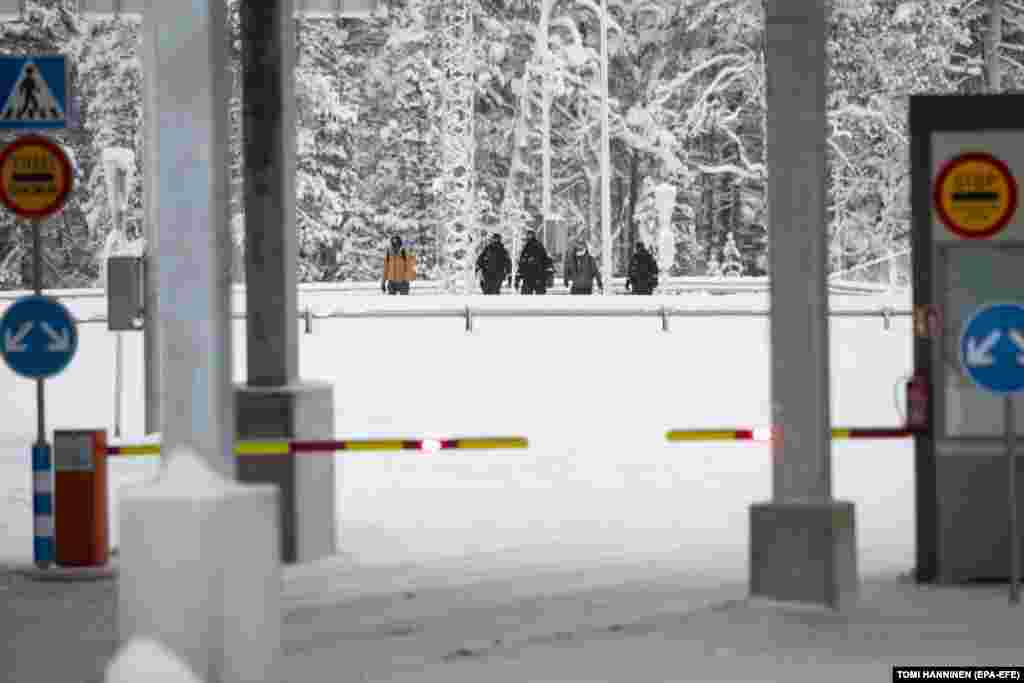 Migranții sunt însoțiți de polițiștii de frontieră finlandezi când ajung la stația de frontieră Raja-Jooseppi din Laponia pe 27 noiembrie. Potrivit poliției de frontieră finlandeză, aproximativ 900 de solicitanți de azil din țări precum Afganistan, Kenya, Maroc, Pakistan, Somalia, Siria și Yemen au traversat granița Finlandei din Rusia în noiembrie, o creștere spectaculoasă de la mai puțin de unul pe zi în octombrie.