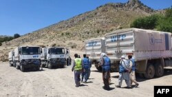 لاری ها و کارمندان برنامه جهانی غذا که کمک ها را به مناطق مختلف افغانستان منتقل می کنند 