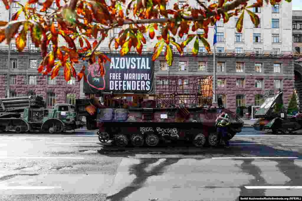 Згорілий російський БТР на тлі плаката зі закликом звільнити з полону оборонців Маріуполя та заводу &laquo;Азовсталь&raquo;. Підготовка до своєрідного&nbsp;&laquo;параду&raquo; знищеної техніки російських загарбників до Дня Незалежності України. Центр Києва, 21 серпня 2023 року