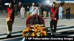 په خیبر کې د وژل شوي پولیس افسر عدنان اپرېدي د جنازې مراسمو کې پولیس سرتېري هغه ته سلامي کوي ـ د جولای ۲۵مې انځور.