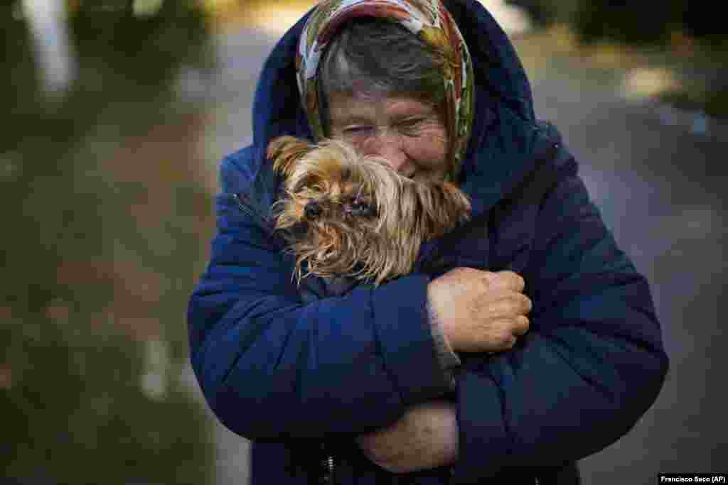 A woman warms her dog in her coat in Kivsharyvka on October 16, 2022. Residents had been living without gas, electricity, or running water.&nbsp;