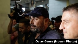 Fostul ministru Darius Vâlcov este flancat de polițiști pe Aeroportul Otopeni, în ziua în care a fost extrădat din Italia, 14 august 2023.