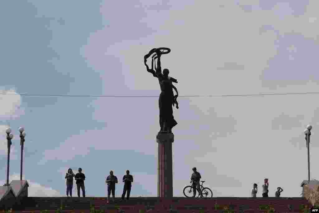 Жителите ја гледаат делумно поплавената област додека водите се зголемуваат во Херсон.