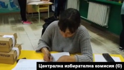 Жена, вероятно член на Секционната избирателна комисия, допълва преференции след края на изборния ден.