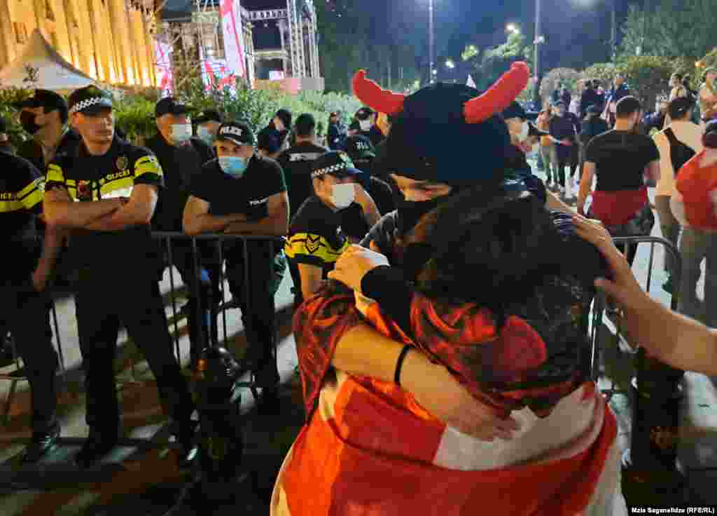 Oameni se îmbrățișează lângă un cordon de securitate în apropierea clădirii parlamentului din Tbilisi. Partidul de guvernământ Visul Georgian și-a anunțat planurile de a reintroduce proiectul de lege, după ce o versiune anterioară a fost abandonată în 2023. Această nouă versiune omite sintagma &bdquo;agent străin&rdquo;.