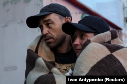 Чоловік і жінка несуть кота під час евакуації із затопленої території після пошкодження дамби Каховської ГЕС, Херсон, 6 червня 2023 року