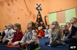 Діти граються в бомбосховищі в підвалі дитячого садка в Києві під час російського вторгнення в Україну. 20 березня 2023 року