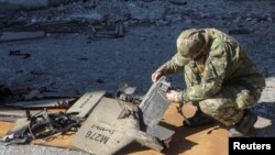 یک سرباز اوکراینی لاشهٔ طیاره بدون سرنشین را که از بین برده شده است٬ معاینه می کند