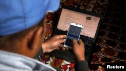 په پاکستان کې یو کس په موبایل ټېلېفون د موسم حال ګوري - پخوانی انځور.