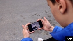 په تهران کې یو کس د پاکستان تر برید وروسته په خپل موبایل ټېلېفون خبرونه ګوري - د جنورۍ ۱۸مې انځور.