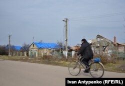 Зруйновані і пошкоджені російськими обстрілами будинки на одній з вулиць Посад-Покровського. Частин дахів закриті плівкою. Початок березня 2023 року