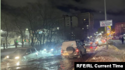 Коли преминават през наводнена от спукания тръбопровод улица в Новосибирск, 11 януари 2024 г.