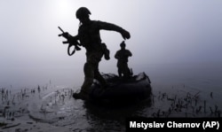 Український військовослужбовець вистрибує з човна біля берега Дніпра на Херсонщині, 15 жовтня 2023 року