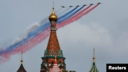 Реактивные самолеты Су-25 выпускают дым в цветах государственного флага над собором Василия Блаженного во время военного парада в российский "День Победы". Москва, 9 мая 2024 года