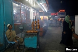 A woman walks past a food vendor in Kabul. (file photo)