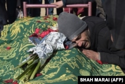 An Afghan relative reacts alongside the body of Saeed Jawad Hossini, 29, who was killed in a suicide attack on a minibus carrying employees of Afghan TV channel TOLO in Kabul in January 2016.