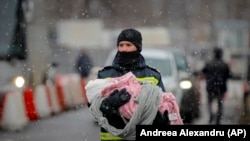 Dramatismul sosirii valurilor de refugiați, inclusiv pe ninsoare și frig, a lăsat fără cuvinte și angajații autorităților. Un pompier ISU ține în brațe un copil ucrainean, la vama Siret, la început de martie.