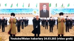 Туркменские старейшины и чиновники на фоне изображения президента Сердара Бердымухамедова, который занял пост в марте 2022 года вместо отца. Собеседники Азатлыка говорят, что портреты Сердара и Гурбангулы Бердымухамедовых висят повсюду, их нет «разве что в туалетах»