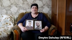 Viktoria Vovk holds portraits of her son and son-in-law. "They tormented our children. For what? They didn't hurt anyone!"