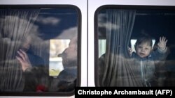 Un copil ucrainean face cu mâna dintr-un microbuz care transportă refugiați preluați de la punctul de frontieră Palanca, 12 aprilie 2022 