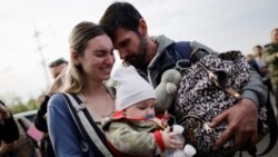 O familie de ucraineni evacuați de la Mariupol se îmbrățișează după ce au ajuns la un centru de înregistrare a persoanelor strămutate din Zaporojie - 3 mai 2022 