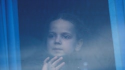 O fată se uită prin geamul autobuzului în timp ce civilii evacuați de la oțelăria Azovstal din Mariupol ajung la un centru de cazare temporară din satul Bezimenne. 