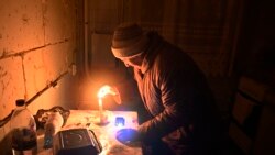 O femeie aprinde o lumânare în apartamentul ei dintr-un bloc de locuințe, distrus parțial după bombardamentele rusești. Foto: Serghei Șuzavkov / AFP)