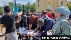 Утилизация алымына қарсы митингіге жиналғандар үкіметке талабы жазылған қарарға қол қойып жатыр. Алматы,  17 сәуір, 2022 жыл.