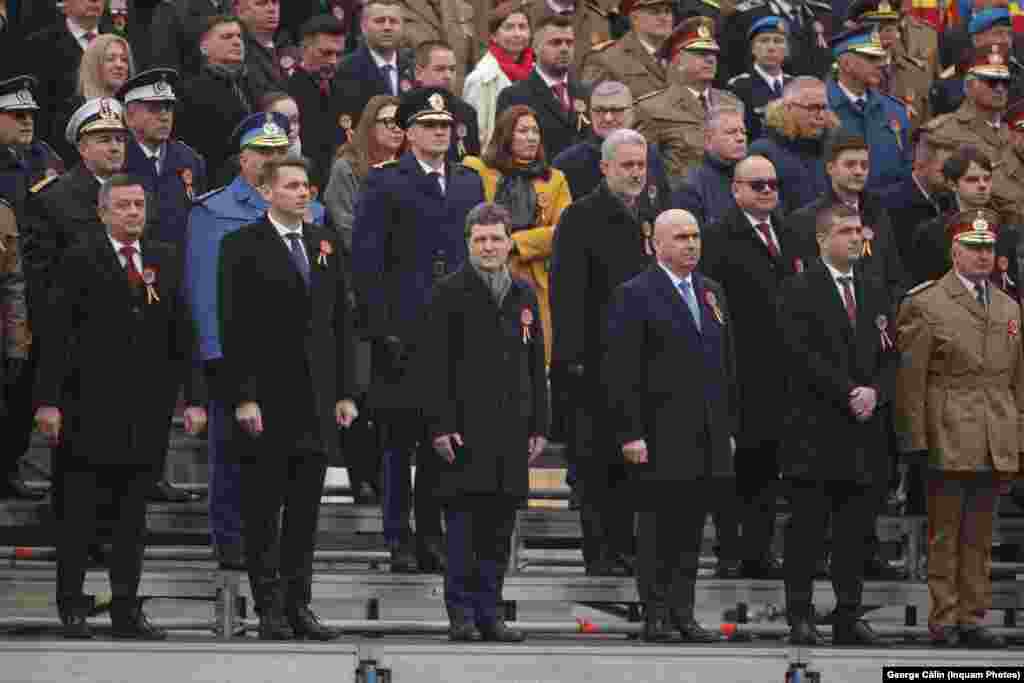 În primul rând al invitaților la parada militară de 1 Decembrie, de la Arcul de Triumf, se află președintele României, Nicușor Dan, iar în stânga sa se află premierul Ilie Bolojan și ministrul interimar al Apărării, Radu Miruță. În dreapta președintelui se află președintele Senatului, Mircea Abrudean, iar în dreapta acestuia, președintele Camerei Deputaților, Sorin Grindeanu.