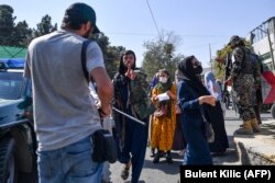 A member of the Taliban spots the camera of a foreign journalist during the protest.