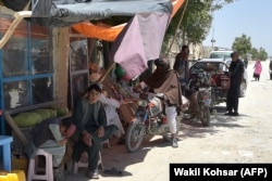 Taliban fighters stand along a road with their motorcycles at a local bazaar in the Andar district of Ghazni Province on June 3.