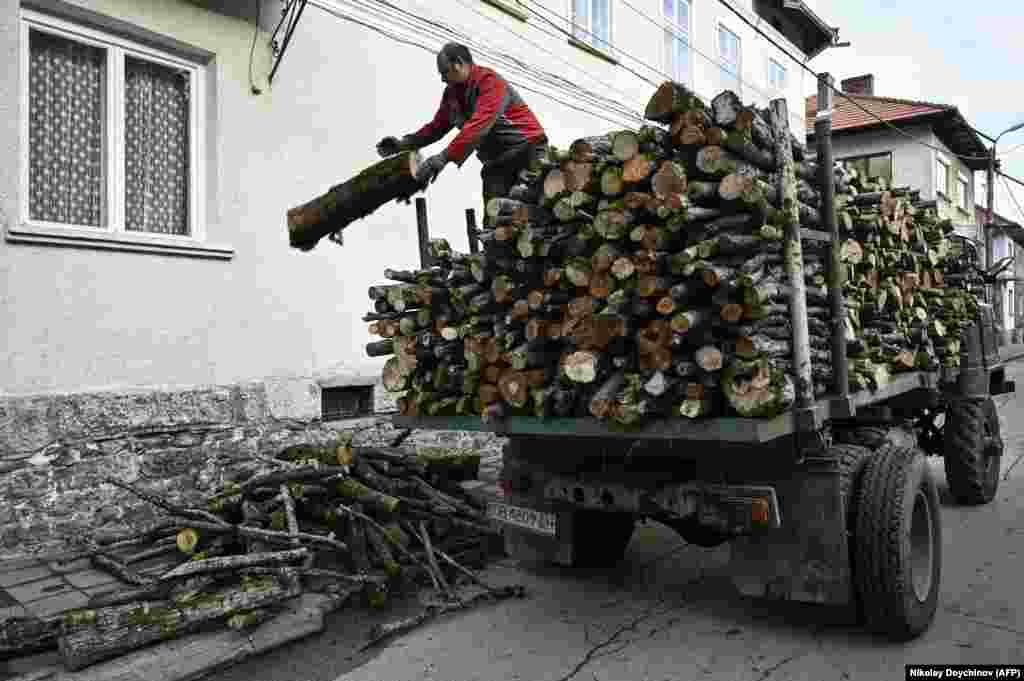 Маж истоварува огревно дрво од камион пред куќа во Тетевен, Бугарија, на 8 декември. Во Бугарија, минатиот август, беше воведена забрана за извоз на дрво во земји кои не се членки на ЕУ, како одговор на двојно зголемување на цената на огревното дрво во период од една година наспроти големата побарувачка. &nbsp;
