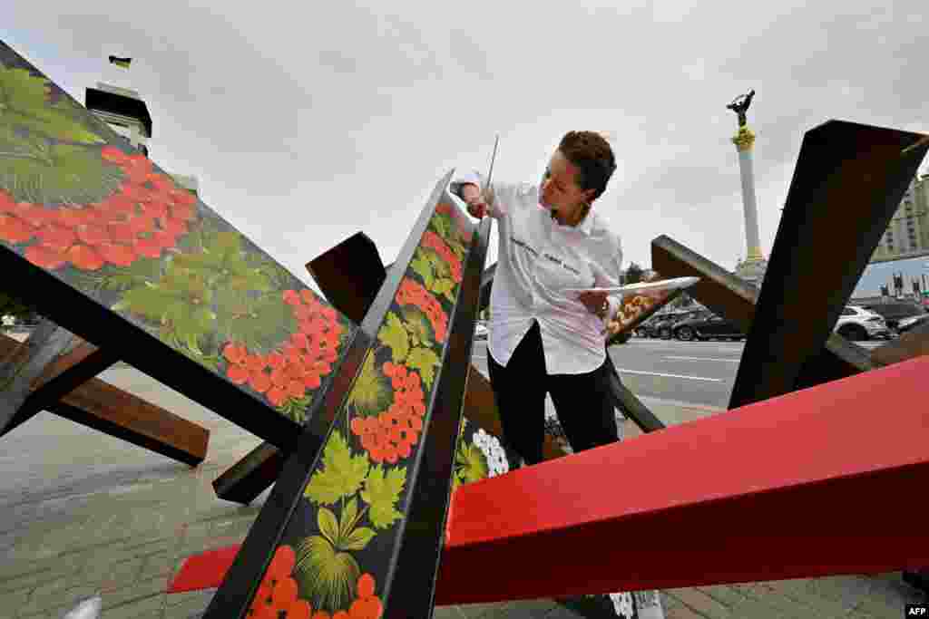 Artista ucraineană Varvara Lohvin pictează motive tradiționale ucrainene pe barierele antitanc din centrul Kievului, în luna august 2022.&nbsp;