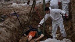 Un muncitor al cimitirului mută un cadavru dintr-o groapă comună din Bucea pe o macara pentru a-l duce la morgă, la identificare