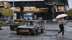 O femeie trece pe lângă o benzinărie distrusă de rachetele rusești, la Dnipro, pe 26 octombrie 2022. REUTERS / Mykola Synelnykov 