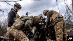 Українські військовослужбовці бригади «Хартія» заряджають снаряд у гаубицю M101, 12 березня 2025 року