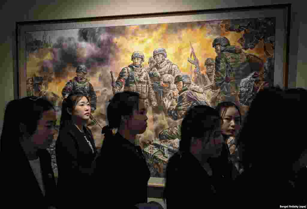Туристы из Северной Кореи проходят мимо картины «Героические борцы за достоинство и честь Родины». В левом верхнем углу полотна видны купола, по-видимому, православной церкви
