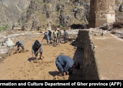 Afghan men working to redirect floodwaters away from the base of the minaret in May 2019.