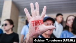 Кыз-келиндерге жана балдарга зомбулук көрсөтүүгө каршы Бишкекте өткөн акция. Жарандык активист Өндүрүш Токтонасыров колуна "Токто!!!" деп жазып чыккан. 8-июль, 2022-жыл. 