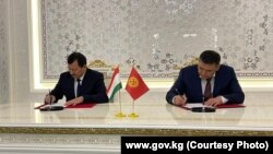 Кыргызстандын Улуттук коопсуздук боюнча мамлекеттик комитетинин (УКМК) төрагасы Камчыбек Ташиев (оңдо) жана Тажикстандын УКМКнын төрагасы Саймумин Ятимов (солдо) протоколго кол коюп жаткан кези.  Дүйшөмбү шаары. 14-ноябрь, 2022-жыл.
