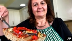 Tiziana di Costanzo, co-founder of Horizon Insects, holds up a slice of pizza made with cricket powder, in her London kitchen. (file photo)