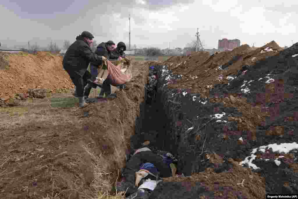 Bodies are placed in a mass grave on the outskirts of Mariupol on March 9, 2022. A nearly three-month-long siege of the port city resulted in the deaths of tens of thousands of inhabitants and the destruction of 90 percent of its structures.