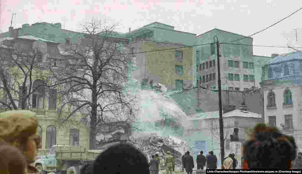 Muncitori îndepărtează dărâmăturile dintr-o clădire distrusă în centrul Bucureștiului. Fotografie a Liviei Cherecheș.