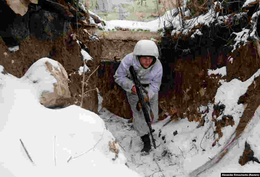 Борец на сепаратистичката група поддржана од Кремљ се движи во ровот свртен кон украинските позиции во селото Жолобок во областа Луганск.