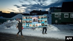 Жители несут предвыборный плакат. Нуук, Гренландия, 11 марта 2025